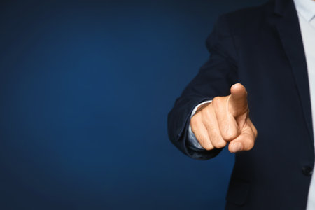 Businessman pointing on color background, closeup view of hand with space for textの写真素材