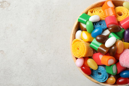 Bowl of delicious colorful candies on gray table, top view with space for textの写真素材