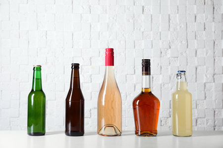 Bottles with different alcoholic drinks on table near white wallの写真素材