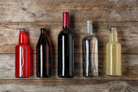 Bottles with different alcoholic drinks on wooden background, top viewの写真素材