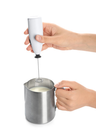 Woman using milk frother device in pitcher on white backgroundの写真素材
