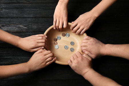 Poor people holding bowl with coins on wooden background, top viewの写真素材