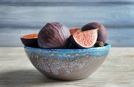 Bowl with fresh ripe figs on wooden background. tropical fruits