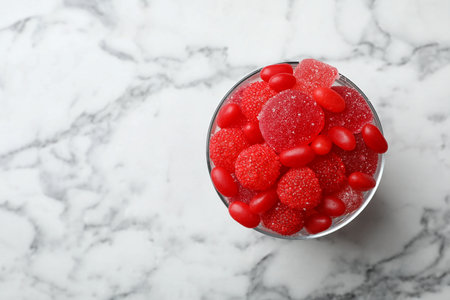 Glass of delicious chewing candies on marble table, top view with space for textの写真素材