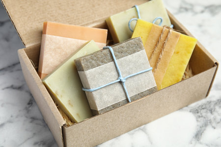Cardboard box with different handmade soap bars on table