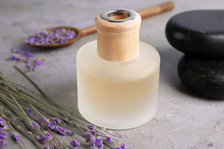 Bottle with natural herbal oil and lavender flowers on color background