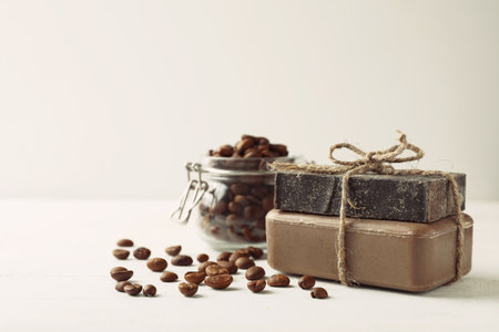 Handmade soap bars and coffee beans on white table. Space for text