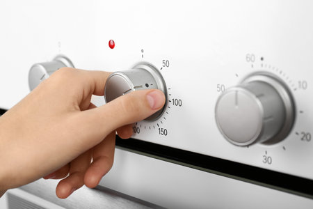 Woman adjusting electric oven, closeup. kitchen appliancesの写真素材