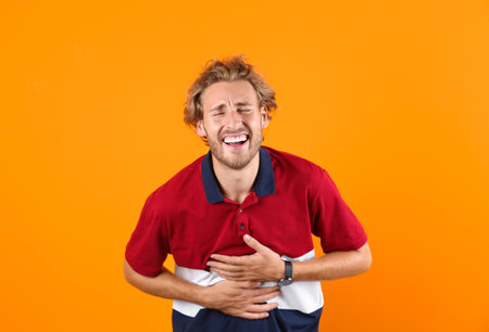 Handsome young man laughing on color backgroundの写真素材