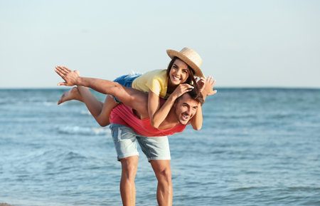 Happy young couple having fun at beach on sunny dayの写真素材