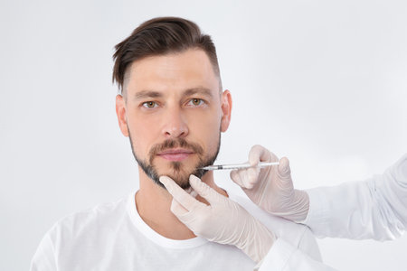 Mature man getting facial injection on white background. cosmetic surgery conceptの写真素材