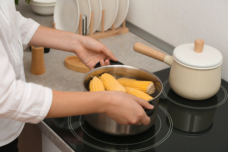 Woman preparing corn in stewpot on stove, closeupの写真素材
