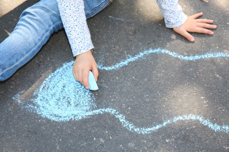 Little child drawing with colorful chalk on asphalt, closeupの写真素材