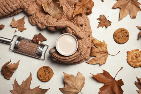 Flat lay composition with hot cozy drink and autumn leaves on light backgroundの写真素材