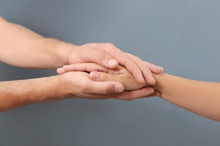 Man holding woman's hand on gray background, closeup. Concept of support and helpの写真素材