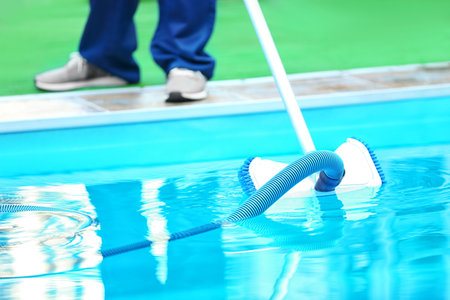 Male worker cleaning outdoor pool with underwater vacuumの写真素材