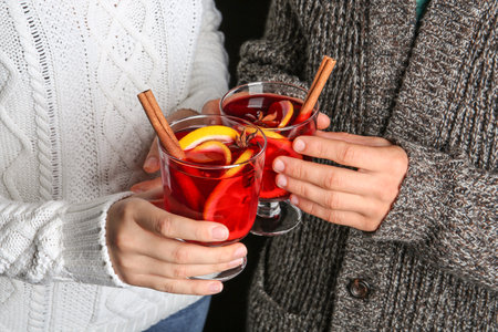 Man and woman holding glasses with hot mulled wine, closeup. romantic holiday momentの写真素材