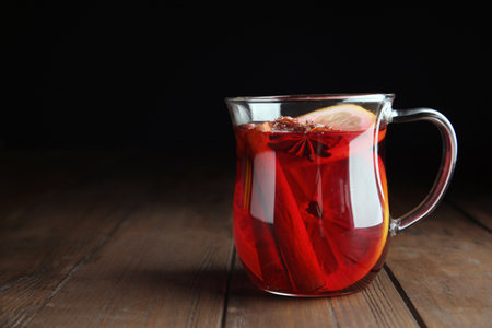 Cup with red mulled wine on wooden table against dark background. Space for textの写真素材