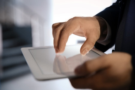 Businessman using digital tablet at workplace, closeup of hand. Mockup for designの写真素材