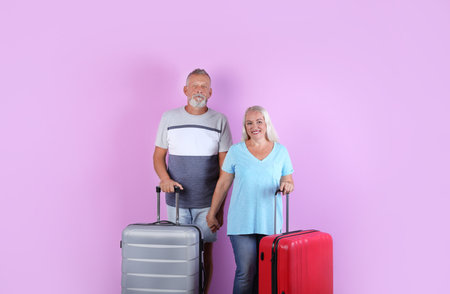 Senior couple with suitcases on color background. vacation travelの写真素材