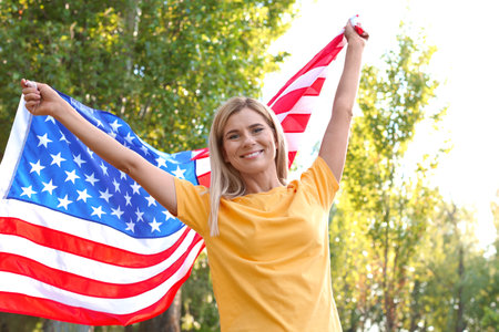 Woman with American flag in park on sunny dayの写真素材