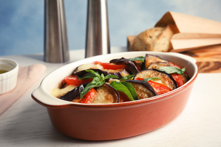 Baked eggplant with tomatoes, cheese and basil in dishware on tableの写真素材