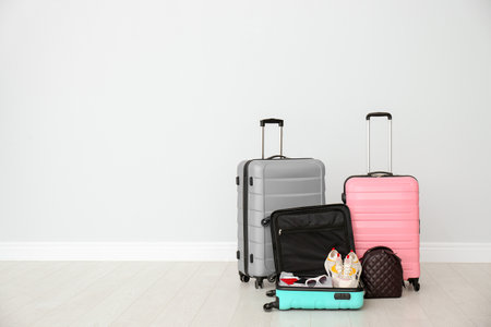 Modern suitcases on floor near light wall. Space for textの写真素材