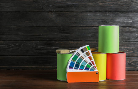 Paint cans, brush and color palette on table against wooden background. Space for textの写真素材