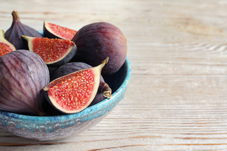 Bowl with fresh ripe figs on wooden background. Space for textの写真素材