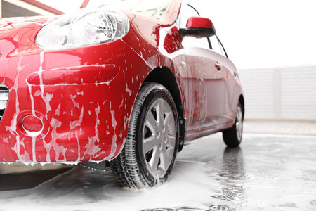Red auto with foam at car wash. cleaning serviceの写真素材