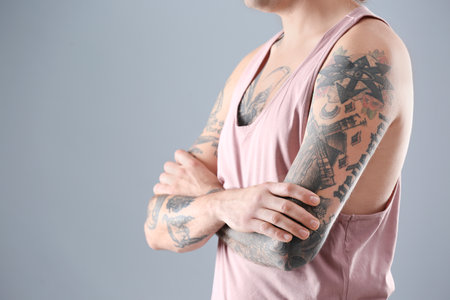Young man with stylish tattoos on gray background. Space for textの写真素材