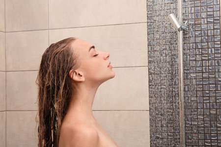 Beautiful young woman taking shower at homeの写真素材