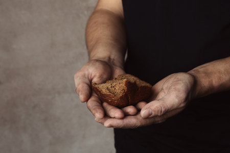 Poor man with piece of rye bread on gray background, closeupの写真素材