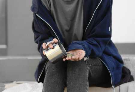 Poor woman counting coins on city street, closeup