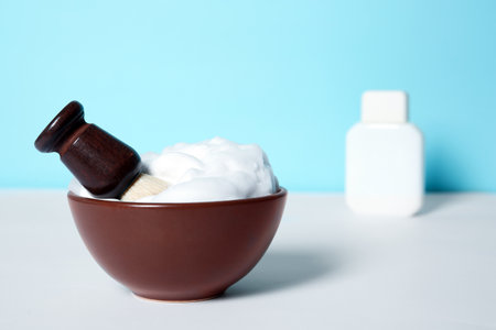 Dish with shaving brush and foam on white table. Space for textの写真素材