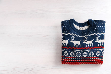 Christmas sweater with pattern and space for text on wooden background, top viewの写真素材