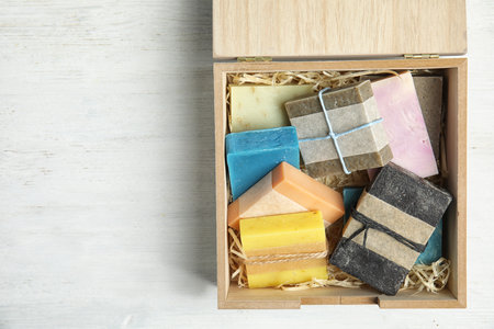Different handmade soap bars in wooden box and space for text on table, top viewの写真素材