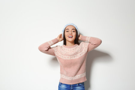 Young woman in warm sweater and knitted hat on white background. Celebrating Christmasの写真素材