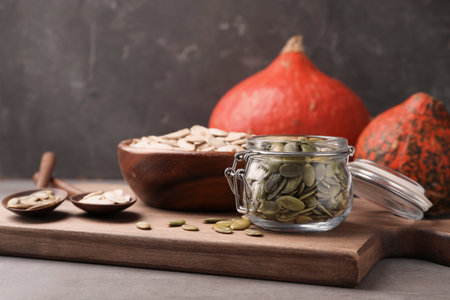 Shelled raw pumpkin seeds in jar on wooden boardの写真素材