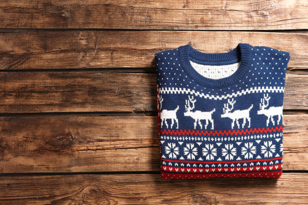 Christmas sweater with pattern and space for text on wooden background, top viewの写真素材