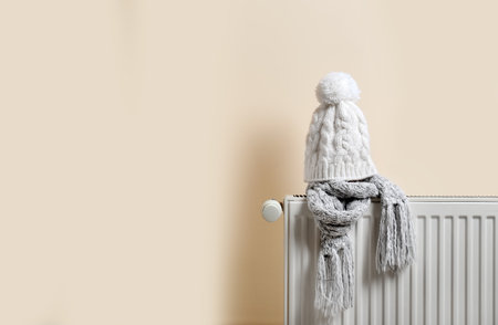 Knitted cap and scarf on heating radiator indoorsの写真素材