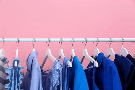 Rack with bright clothes on color backgroundの写真素材