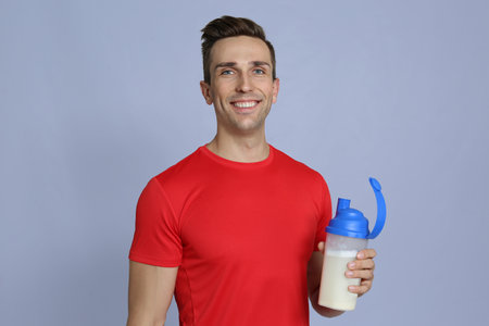 Portrait of man with bottle of protein shake on color backgroundの写真素材
