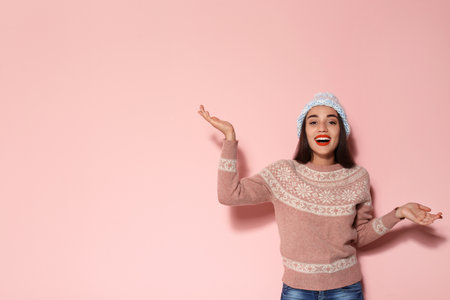 Young woman in warm sweater and knitted hat on color background. christmas celebrationの写真素材