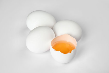 Cracked and whole chicken eggs on white backgroundの写真素材
