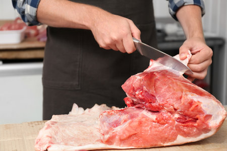 Butcher cutting fresh raw meat on counter in shop, closeupの写真素材