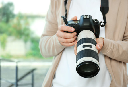 Male photographer with professional camera on blurred background, closeupの写真素材