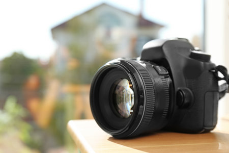 Professional camera on wooden table against blurred background, space for text. Photographer's equipmentの写真素材