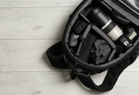 Backpack with professional photographer's equipment on wooden background, top view. Space for textの写真素材