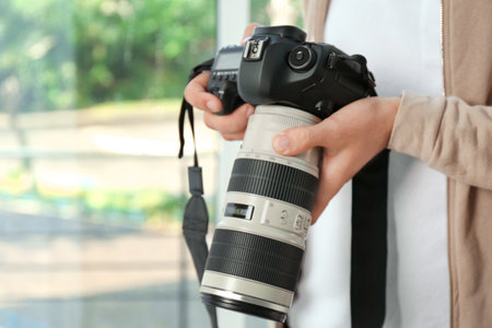 Male photographer with professional camera on blurred background. Space for textの写真素材